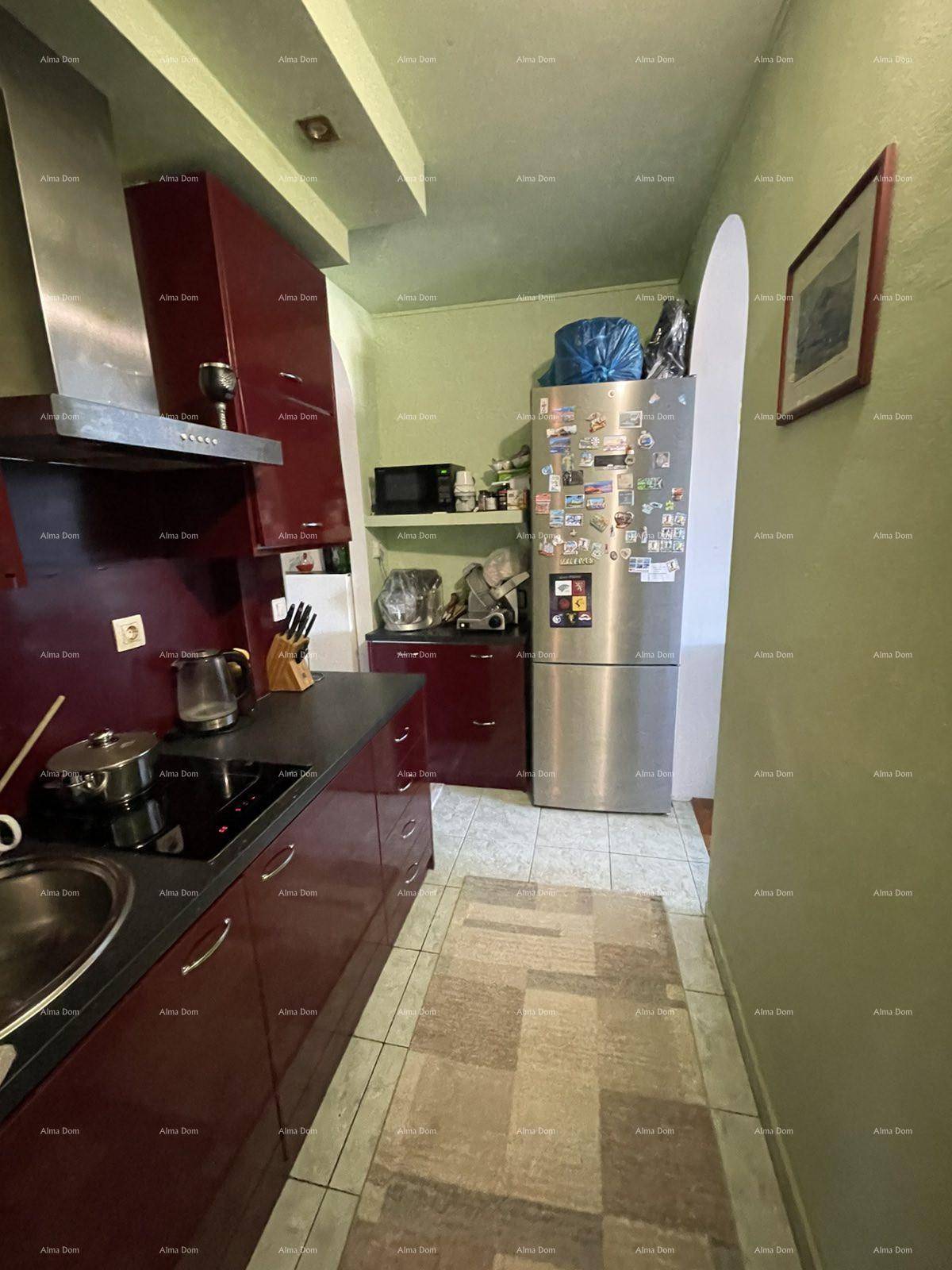 Küche mit roten Schränken, Kühlschrank und Mikrowelle, führt zu einem Flur.