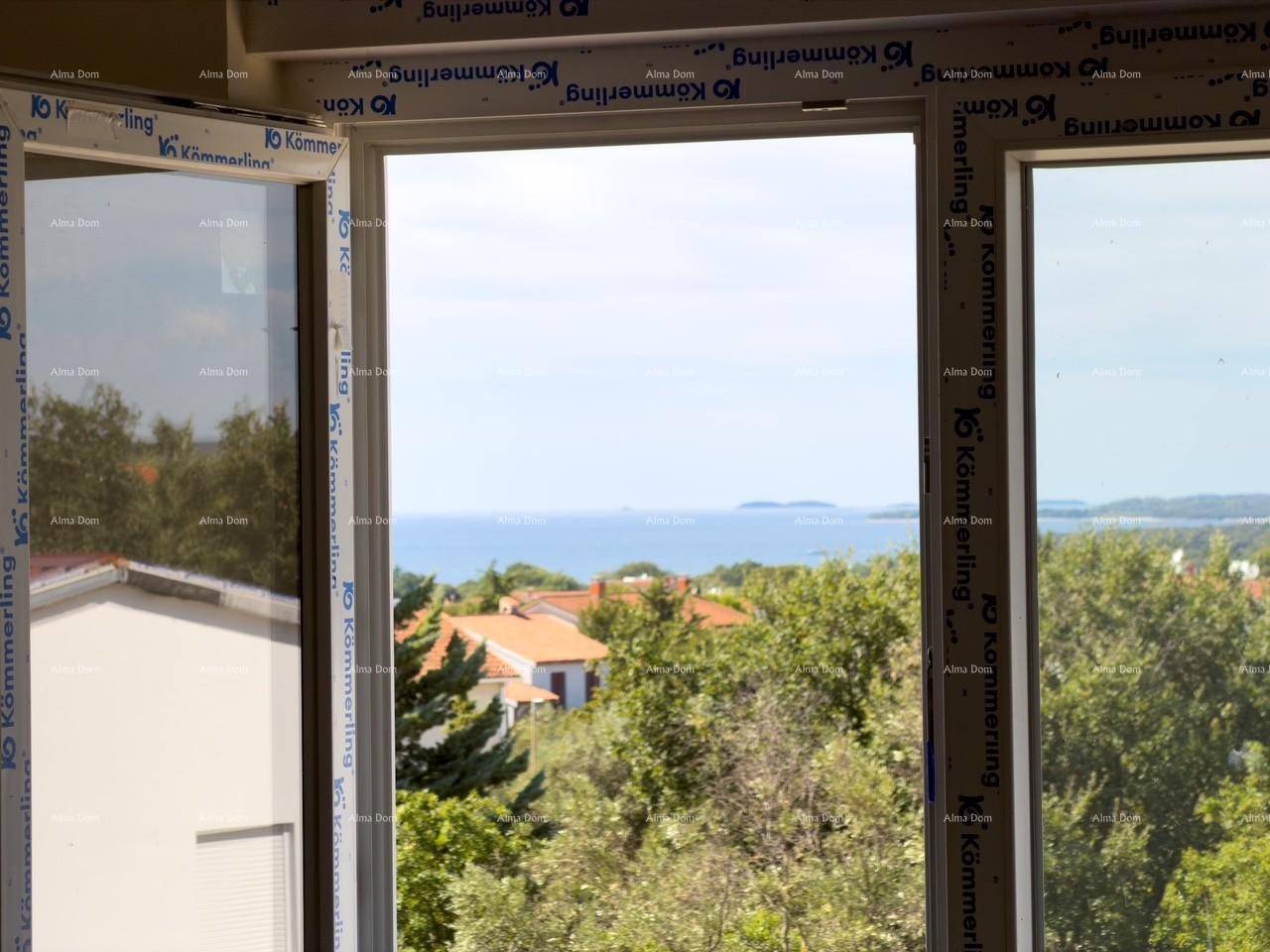 Weitläufiger Meerblick durch ein geöffnetes Fenster über die Baumwipfel.