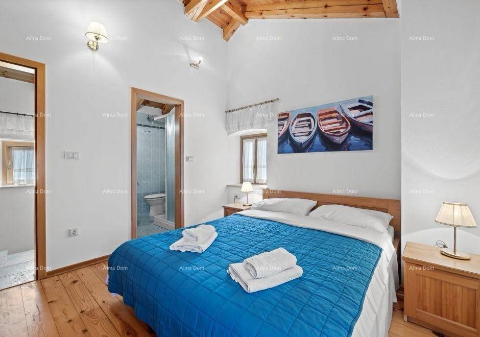 Helles Schlafzimmer mit Doppelbett, Holzboden, Dachbalken und Zugang zum Badezimmer.
