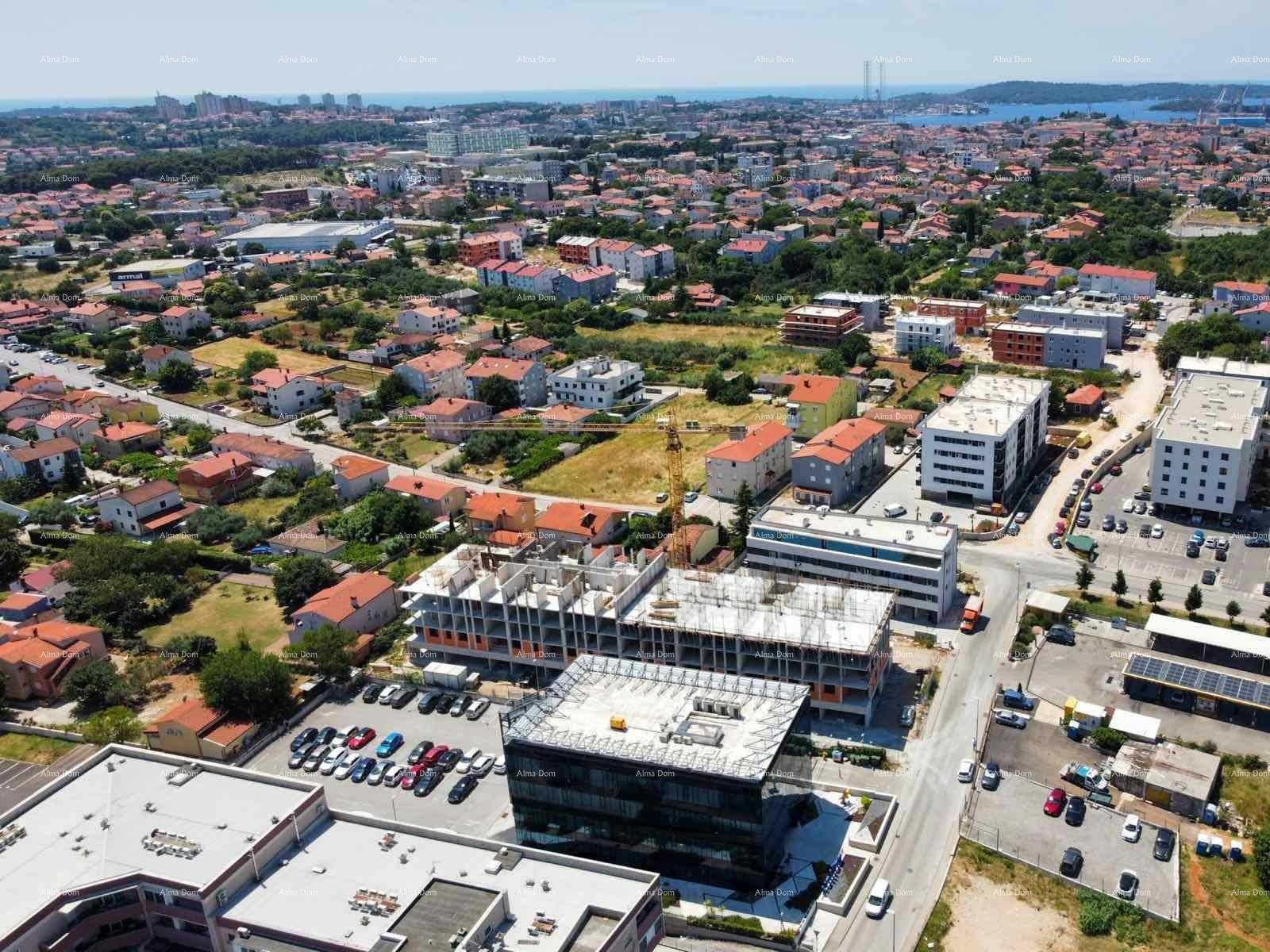 Luftaufnahme einer Baustelle mit umliegenden Wohngebäuden und der Küste im Hintergrund.