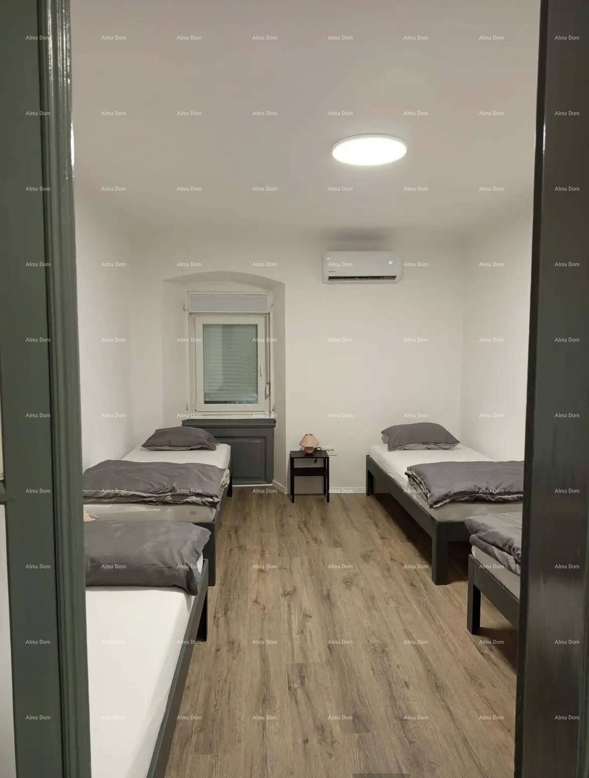Schlafzimmer mit mehreren Einzelbetten, Fenster und Klimaanlage.
