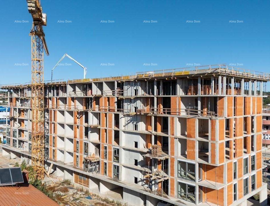 Blick auf die Baustelle des neuen Apartmentgebäudes mit Kränen und unfertigen Etagen.