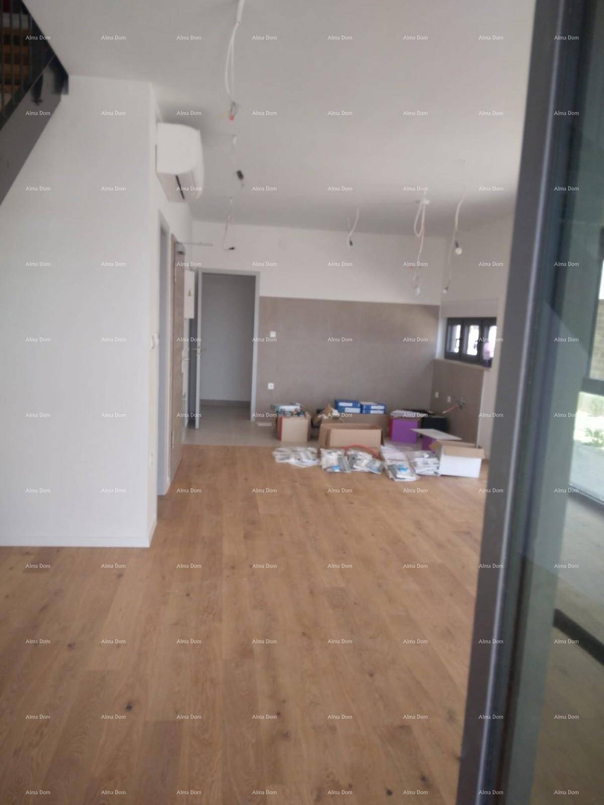 Unfertiger Innenraum mit Holzboden, Baumaterialien und sichtbaren Elektroinstallationen.