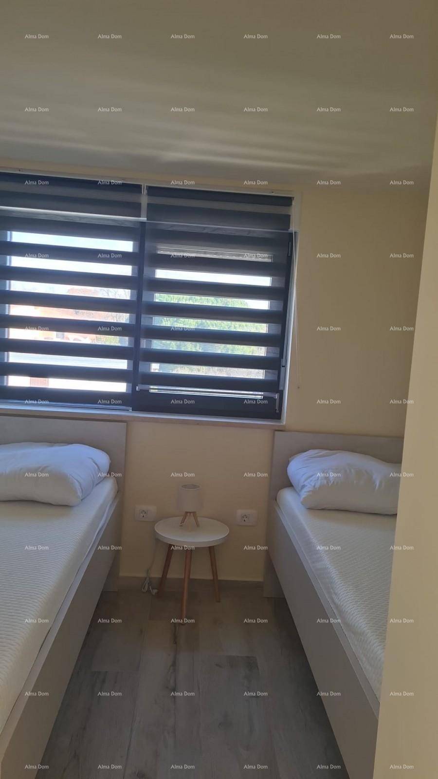 Schlafzimmer mit zwei Einzelbetten, Laminatboden und Fenster mit Jalousien.