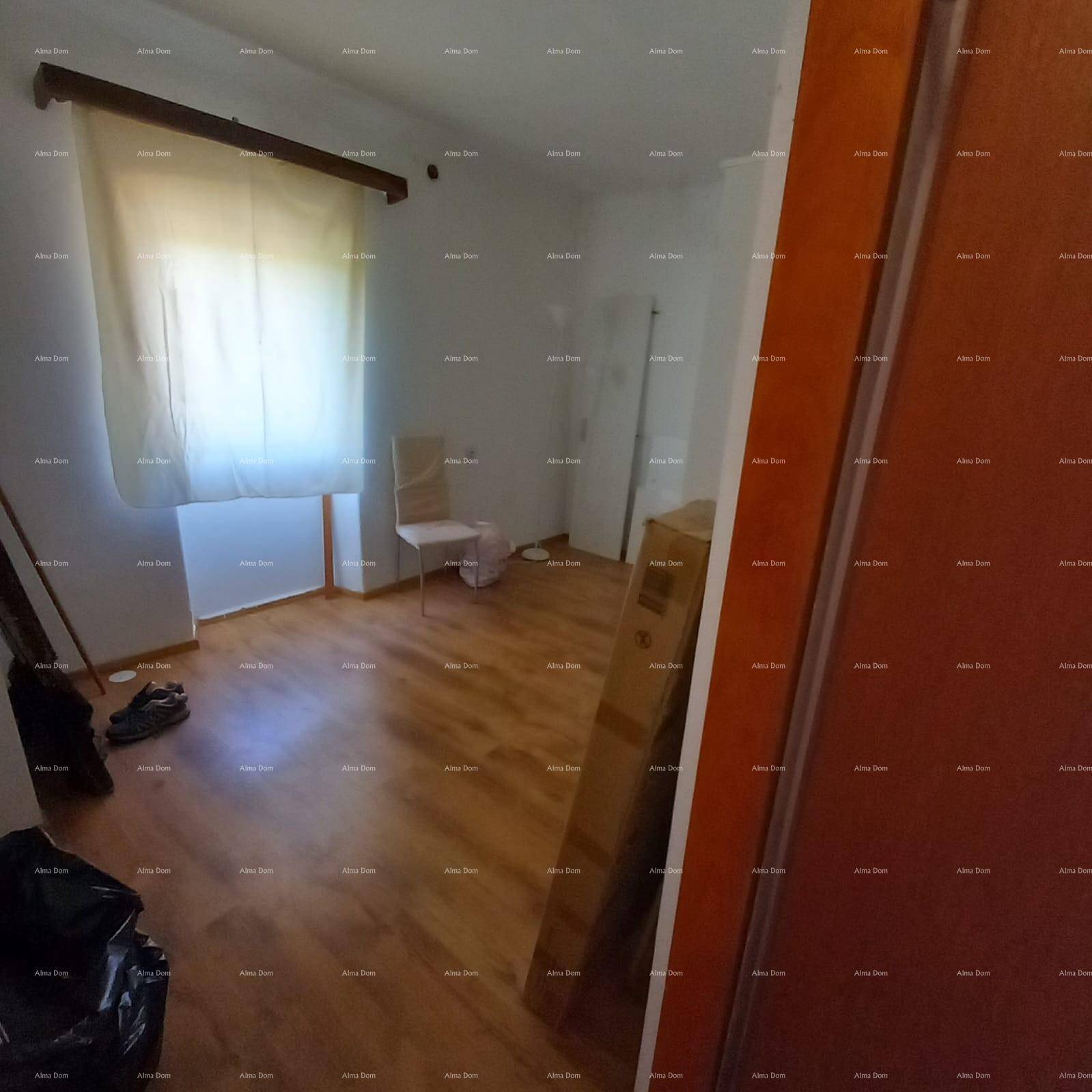 Leeres Zimmer mit Laminatboden und einem Fenster, das viel Tageslicht hereinlässt.
