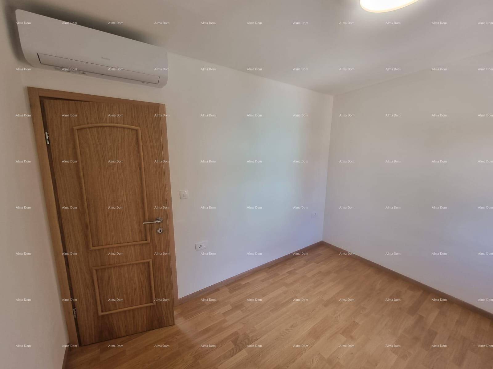 Leeres Zimmer mit Holzboden, weiß gestrichenen Wänden und installierter Klimaanlage.