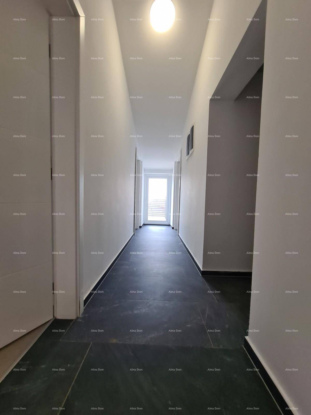 Langer, heller Flur mit dunklem Fliesenboden und weißen Wänden, der zu einem Fenster führt.