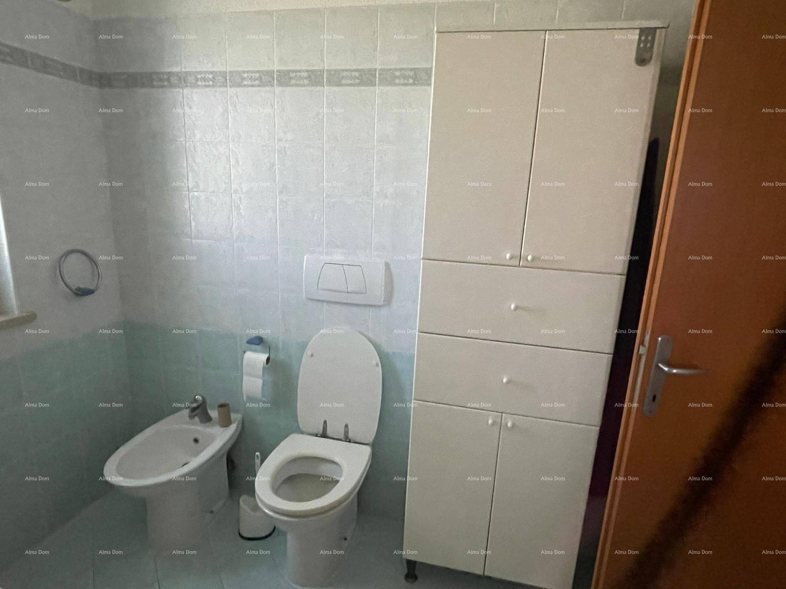 Badezimmer mit Toilette, Bidet und einem hohen weißen Schrank, gefliest in hellblauen und weißen Farben.