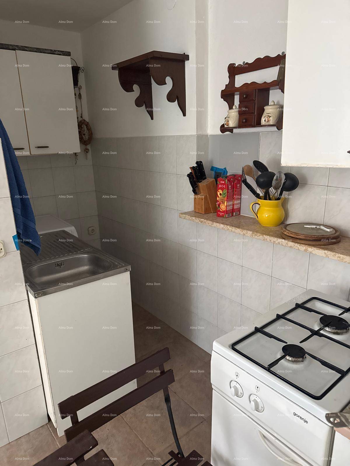 Detailansicht der einfachen Küche mit Gasherd, Spüle und gefliesten Wänden.