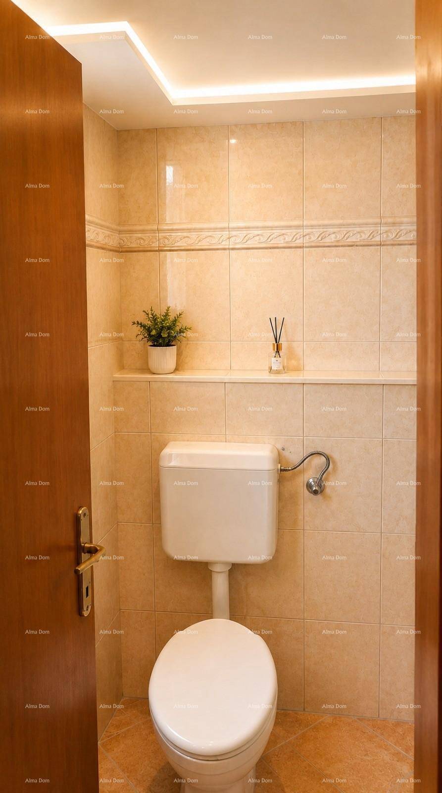 Kleines WC mit beigen Fliesen, einfacher Toilette und Ablagefläche.