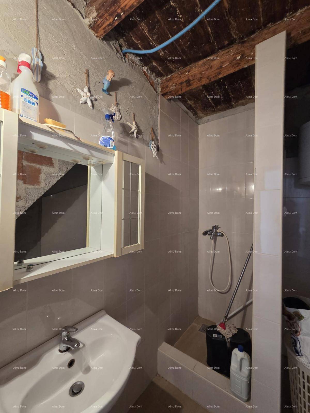 Einfaches Badezimmer mit Waschbecken, Duschbereich und Boiler unter einer rustikalen Holzdecke.