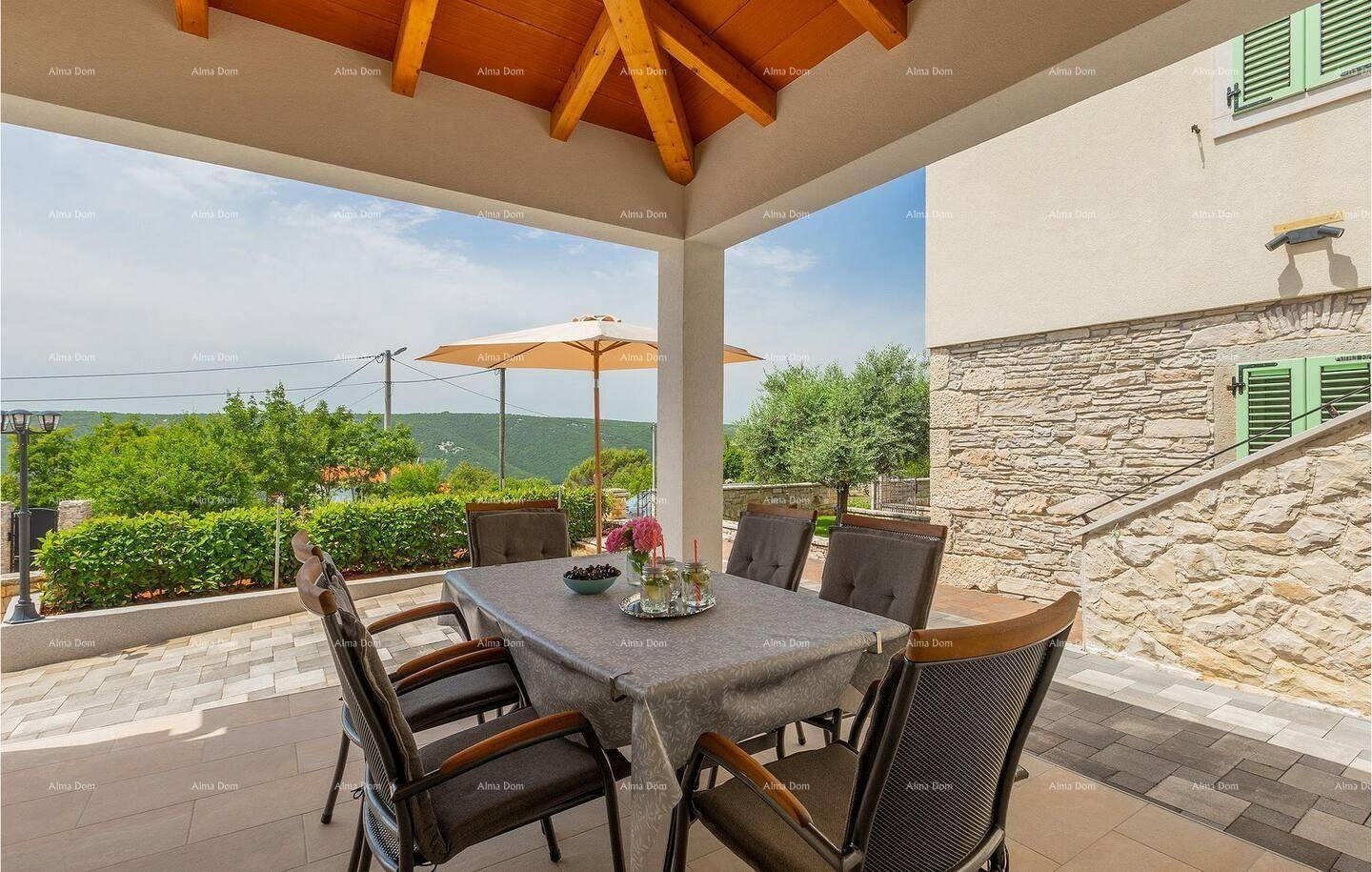 Überdachte Terrasse mit Esstisch und Stühlen, ideal für Mahlzeiten im Freien mit Blick ins Grüne.