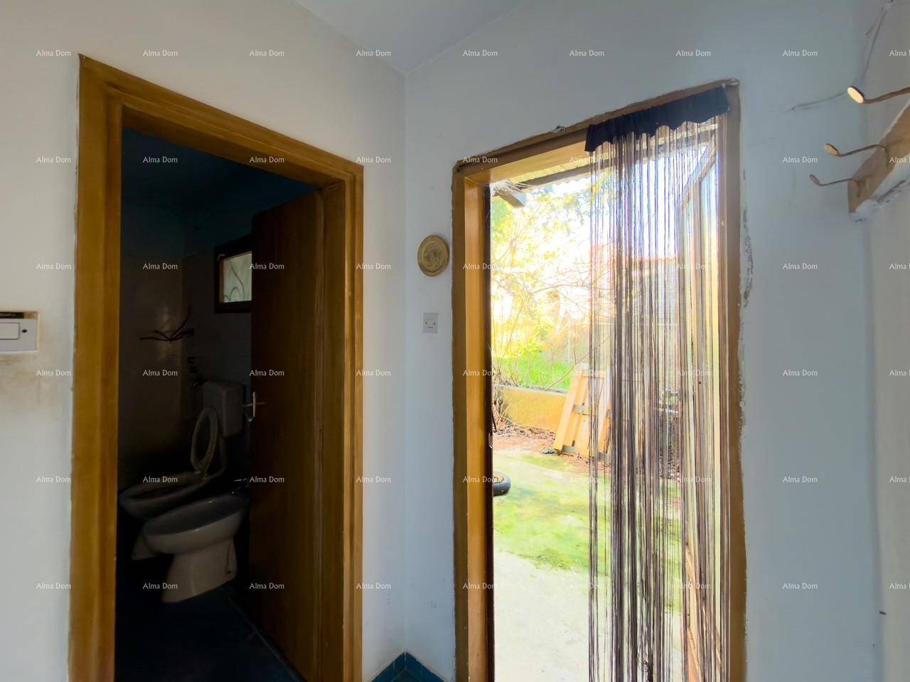 Kleiner Raum mit Zugang zu einer Toilette und einem Blick ins Grüne durch eine Tür mit Vorhang.