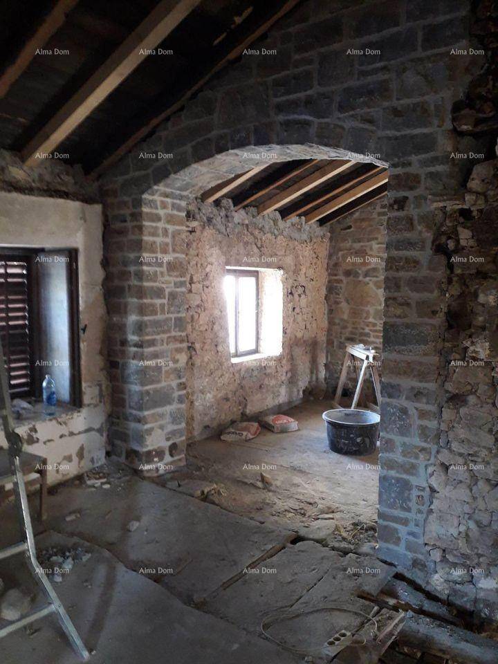 Renovierungsbedürftiger Innenraum mit Steinmauern, Holzbalken und einem Fenster.