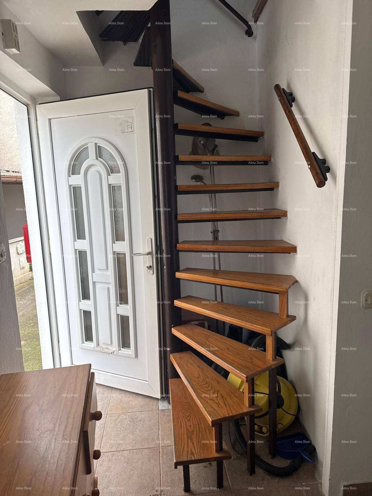 Eingangsbereich mit weißer Haustür und einer eleganten Holz-Wendeltreppe, die in die obere Etage führt.