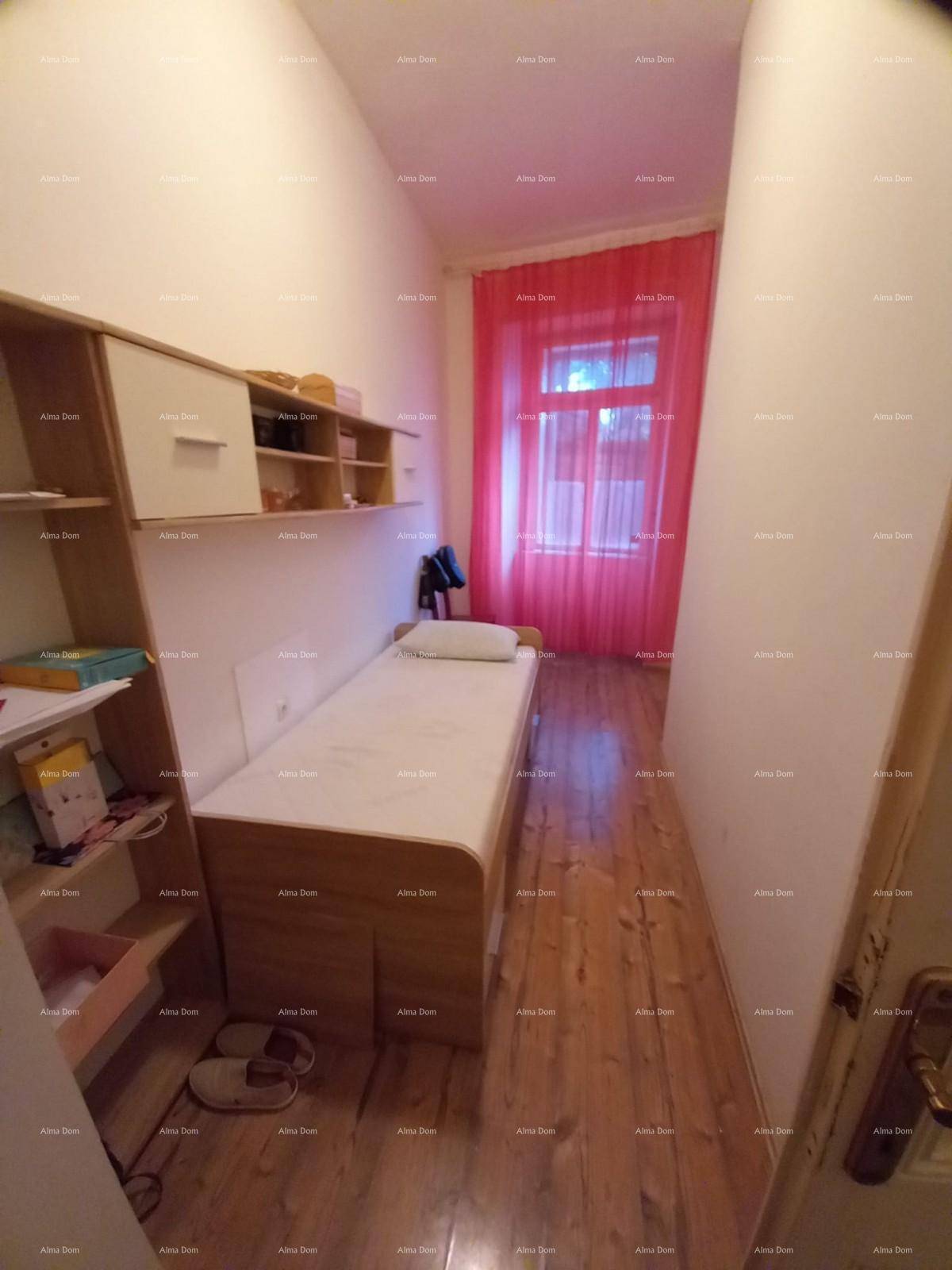 Schlichtes Schlafzimmer mit Einzelbett, Holzboden und roten Vorhängen am Fenster.