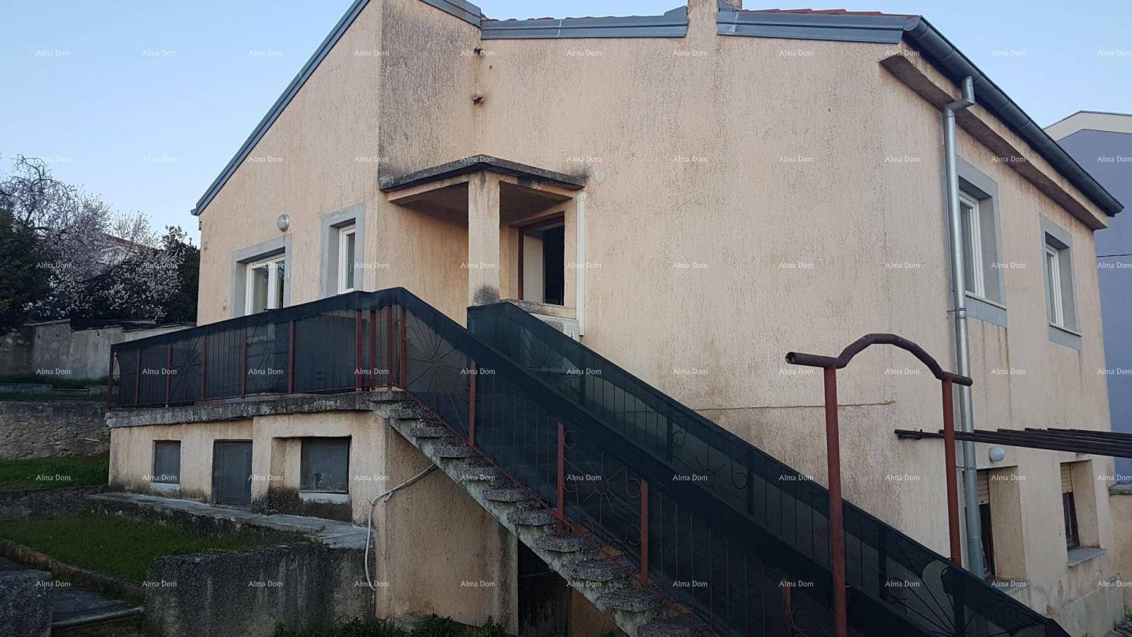 Seitenansicht des Hauses mit Außentreppe, die zu einem oberen Eingang und einem kleinen Balkon führt.