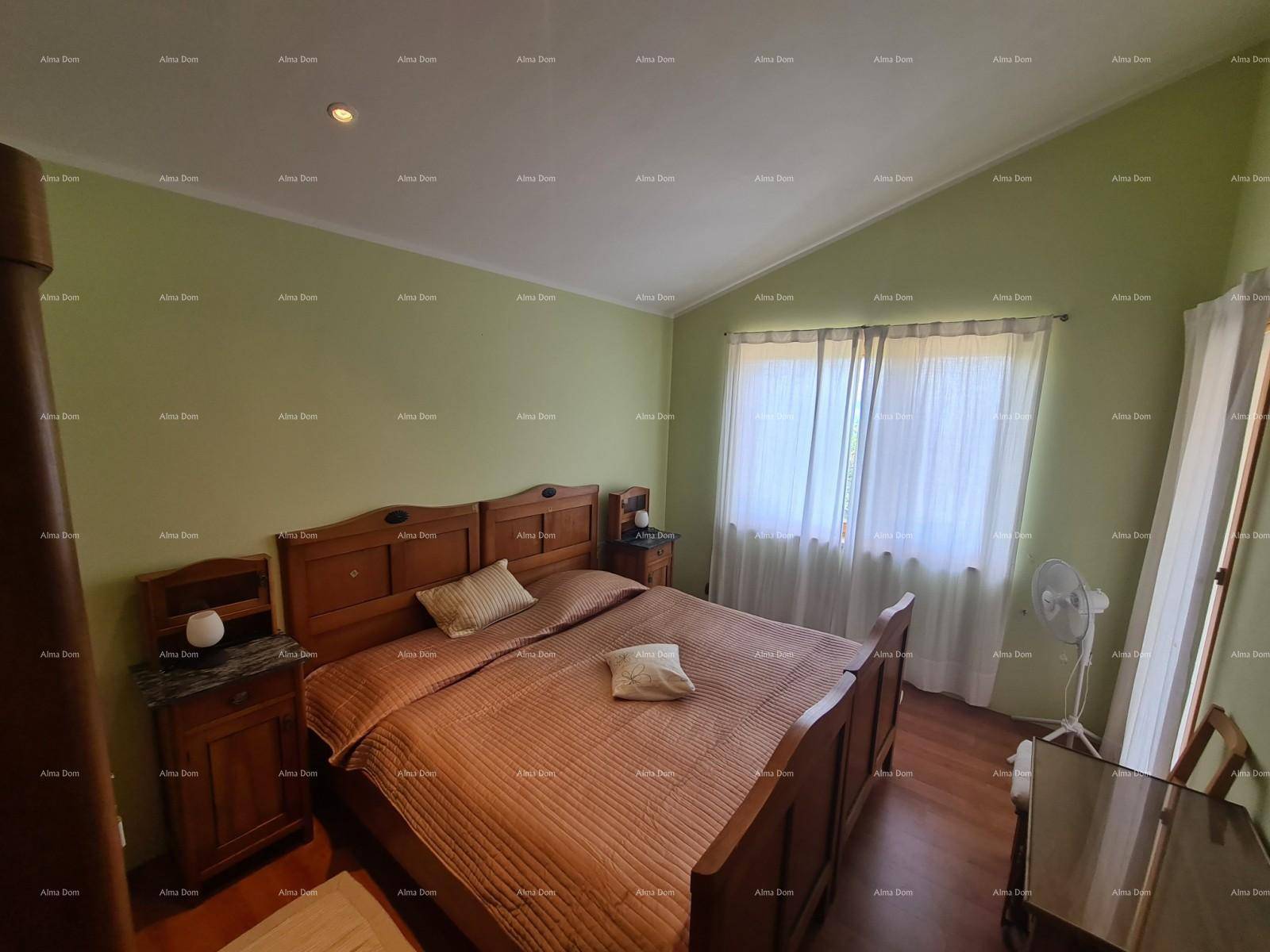 Geräumiges Schlafzimmer mit großem Holzbett, hellgrünen Wänden und schräger Decke.