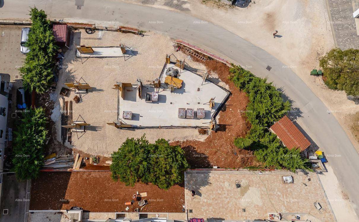 Direkte Draufsicht auf die Fundamentplatte einer Baustelle, umgeben von Erde und jungen Bäumen.