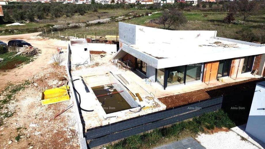 Baustelle einer modernen Villa mit Rohbau des Pools und des Gebäudes in fortgeschrittenem Stadium.
