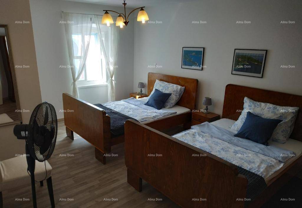 Helles Schlafzimmer mit zwei Einzelbetten, Fenster und einem Ventilator für angenehme Luftzirkulation.