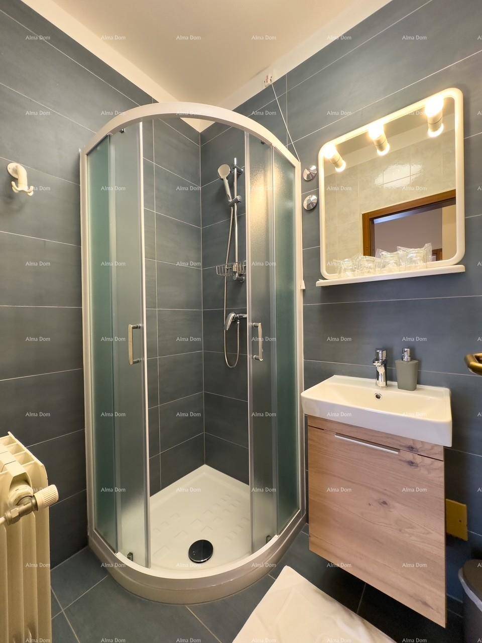 Modernes Badezimmer mit Duschkabine und Waschbecken, ausgestattet mit grauen Wandfliesen und Spiegel.