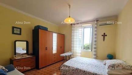 Helles Schlafzimmer mit gelben Wänden, Doppelbett, Kleiderschrank und Klimaanlage.