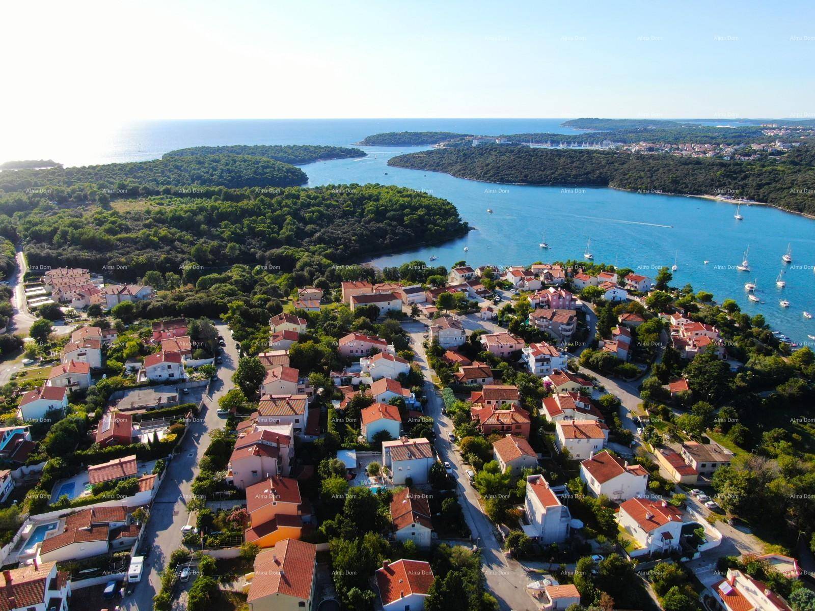 Weitläufige Luftaufnahme einer Küstensiedlung mit roten Dächern und Blick auf das Meer.