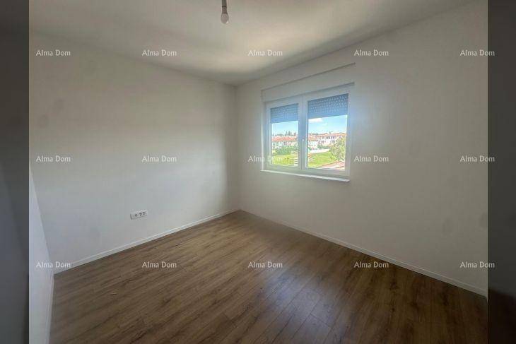 Leeres Schlafzimmer mit hellem Laminatboden und einem Fenster, das Tageslicht hereinlässt.
