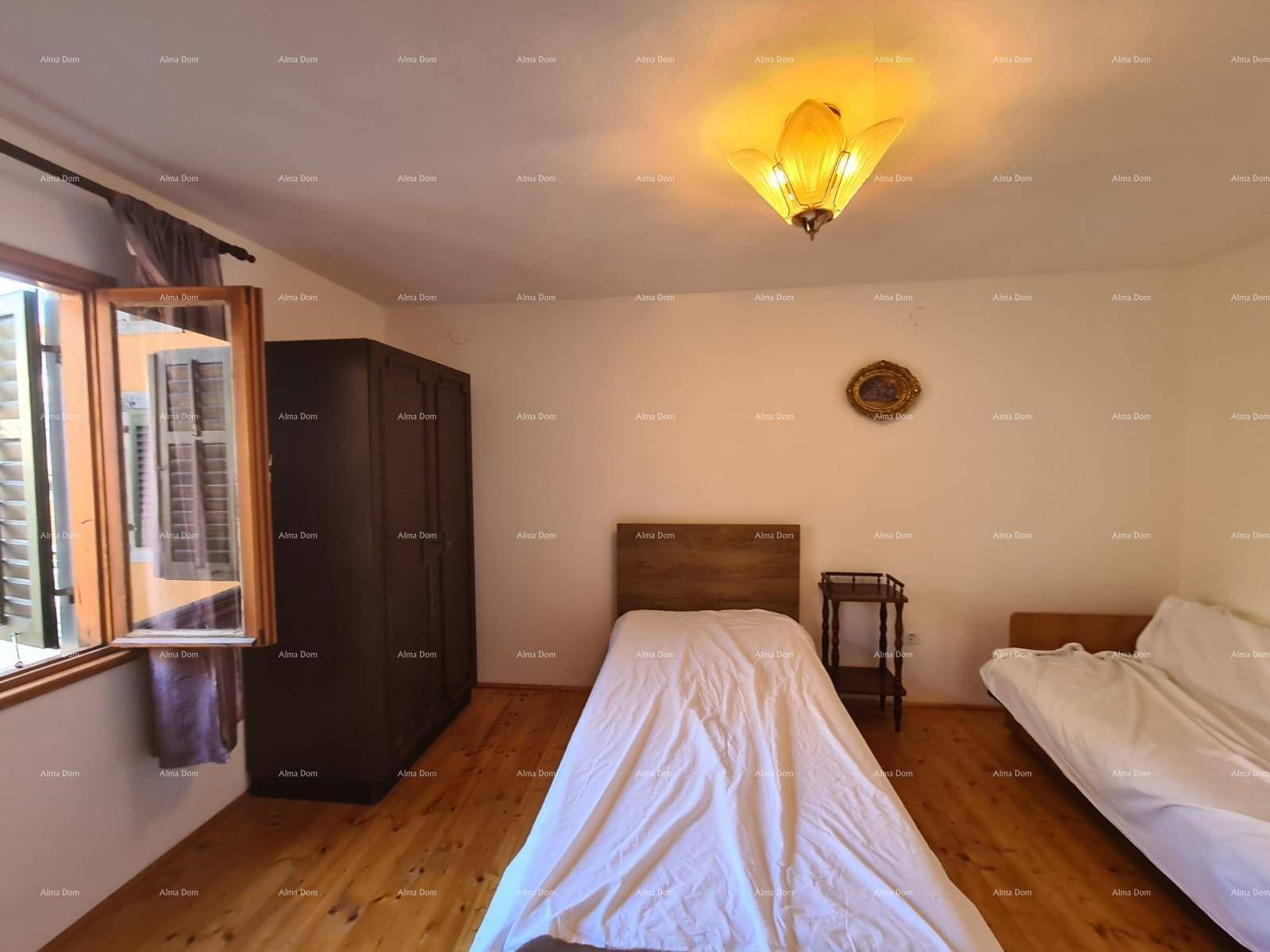 Helles Schlafzimmer mit zwei Einzelbetten, Holzschrank und Fenster mit Fensterläden.