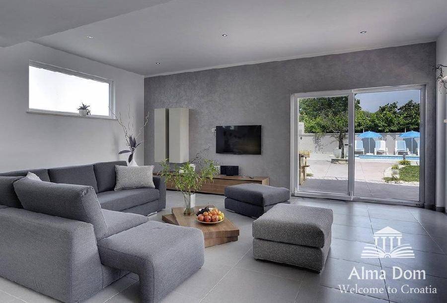 Helles Wohnzimmer mit Zugang zur Terrasse und Blick auf den Poolbereich.