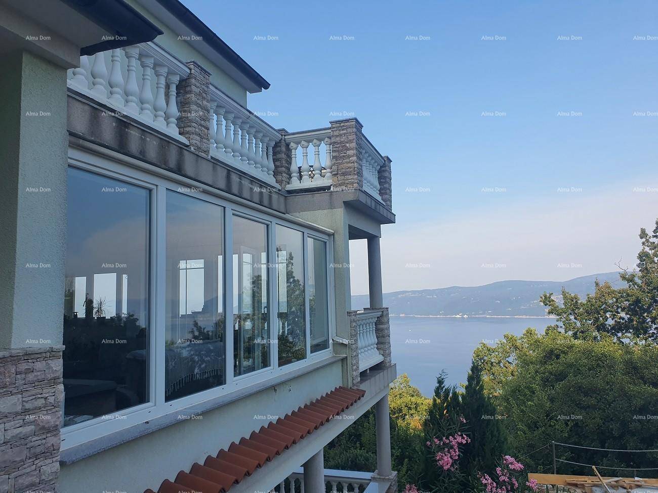 Detailansicht der verglasten Veranda und der Balkone mit Meerblick, umgeben von üppiger Vegetation.