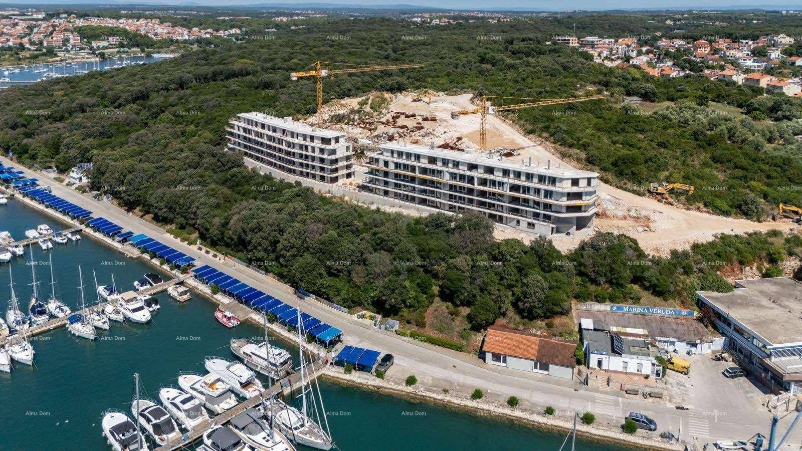 Luftaufnahme einer Baustelle und eines Yachthafens mit Solarpaneelen entlang der Küste.