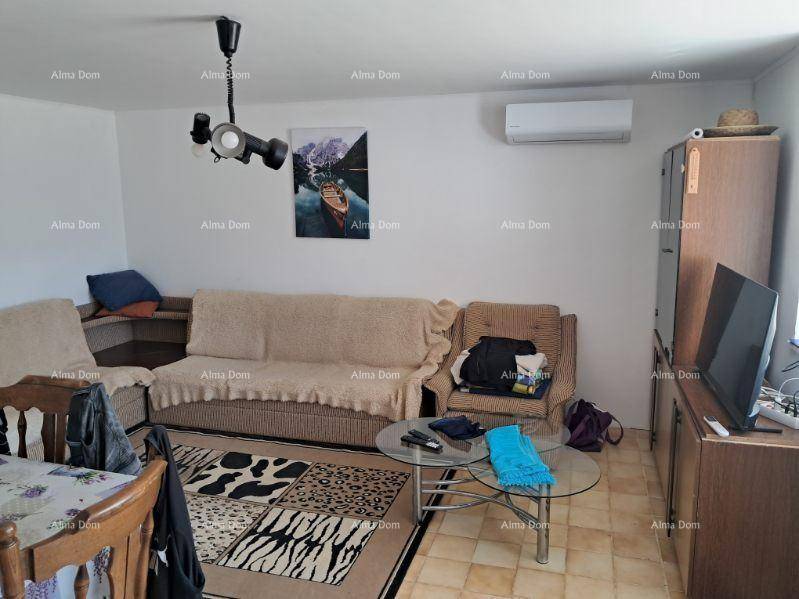 Einfaches Wohnzimmer mit bequemen Sofas, Teppich und Klimaanlage an der Wand.