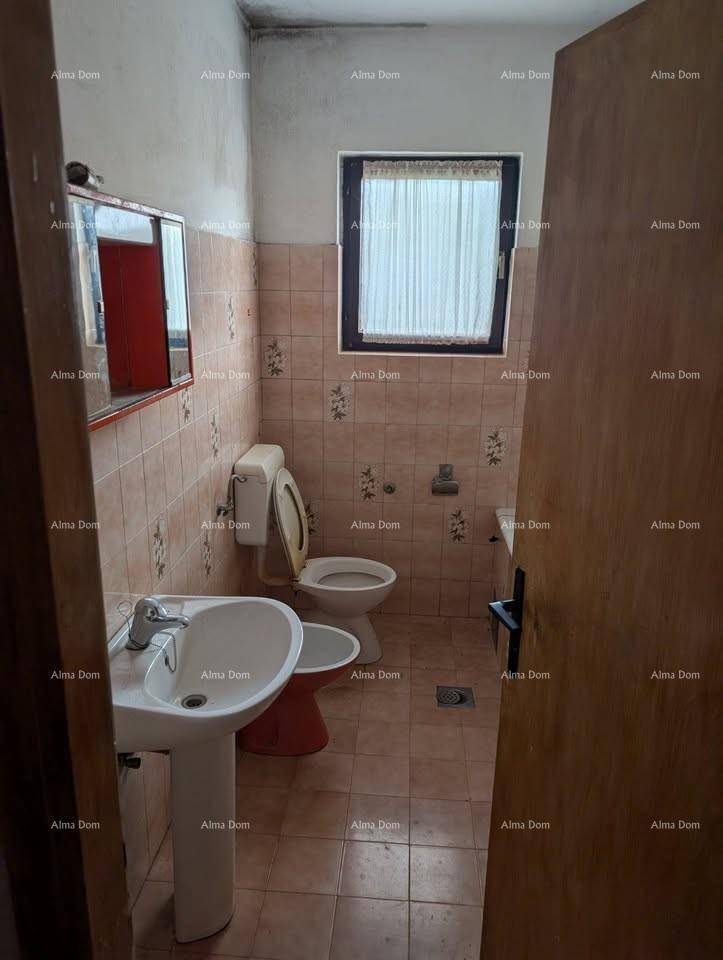 Badezimmer mit rosa Fliesen, Waschbecken, Toilette, Bidet und einem Fenster für Tageslicht.