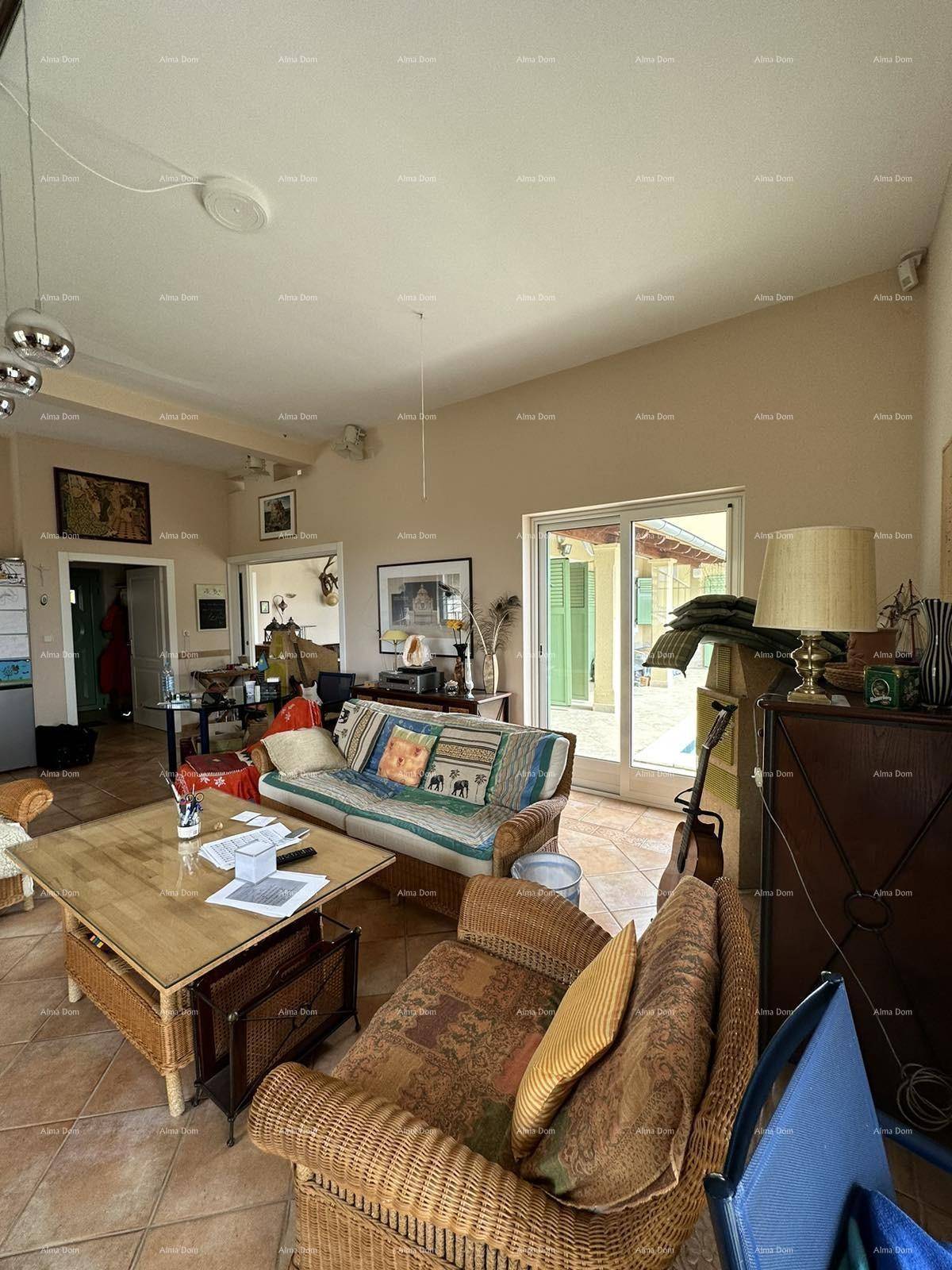 Helles Wohnzimmer mit Korbmöbeln, Fliesenboden und Zugang zur Terrasse.