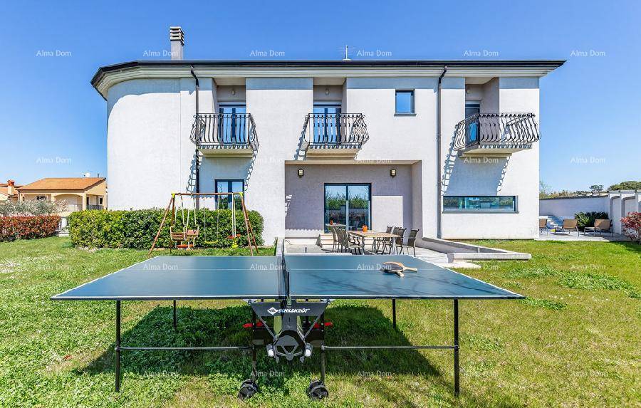 Großer Gartenbereich mit Rasenfläche, Schaukel und Tischtennisplatte hinter der Villa.