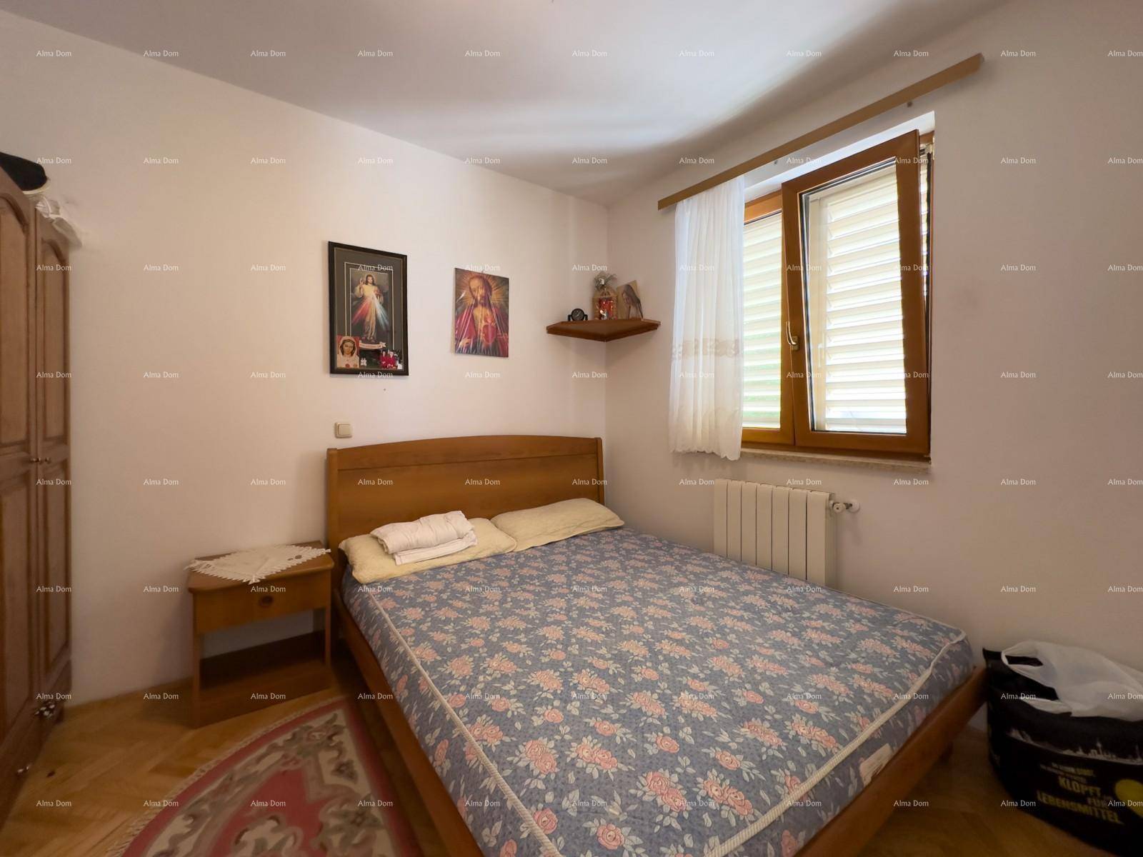 Schlafzimmer mit Doppelbett, Nachttisch und Fenster mit Jalousien.