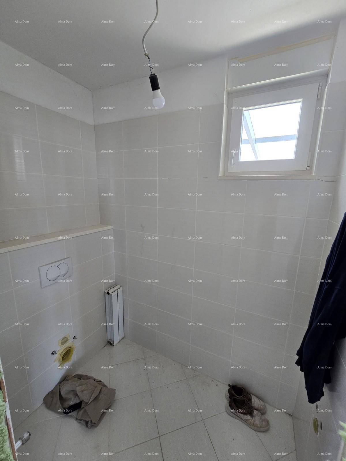 Kleiner WC-Raum im Rohbau mit Fliesenboden und Fenster für Tageslicht.