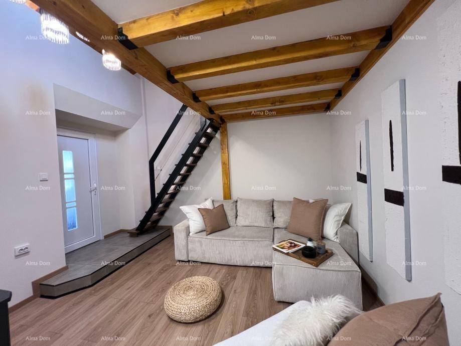 Gemütliches Wohnzimmer mit Sofa, Holzboden und Treppe zum oberen Bereich, unter einer hohen Decke.