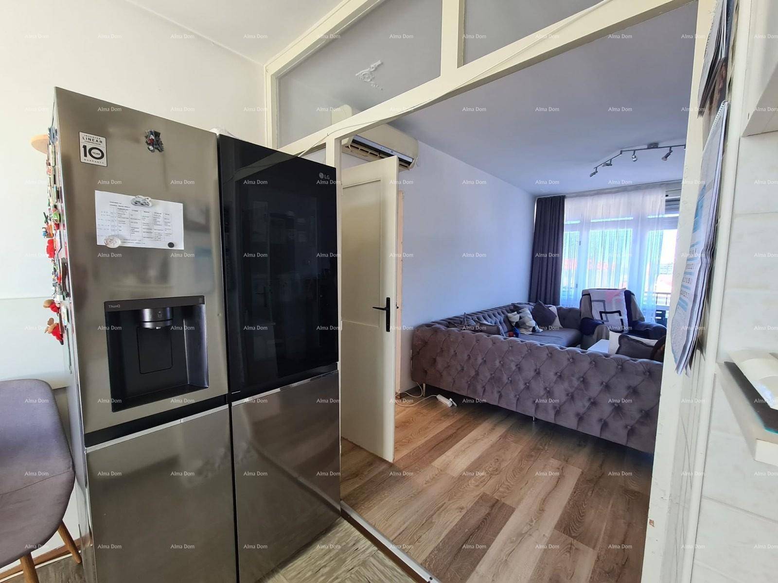 Blick vom Flur in das Wohnzimmer mit großem Sofa und Holzboden.