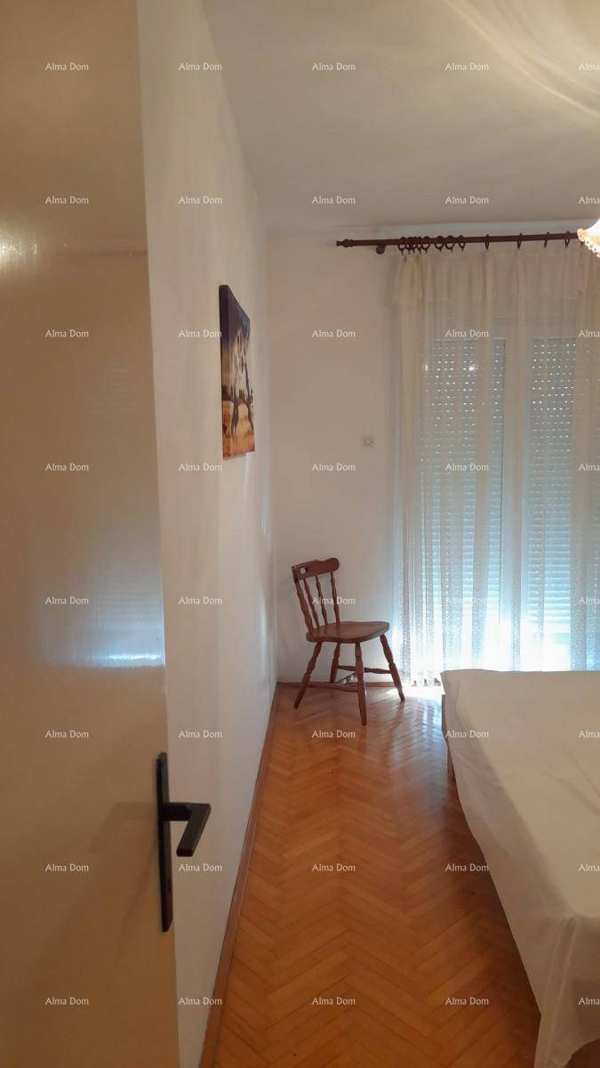 Helles Schlafzimmer mit Parkettboden und einem Fenster mit Rollläden, das viel Tageslicht hereinlässt.