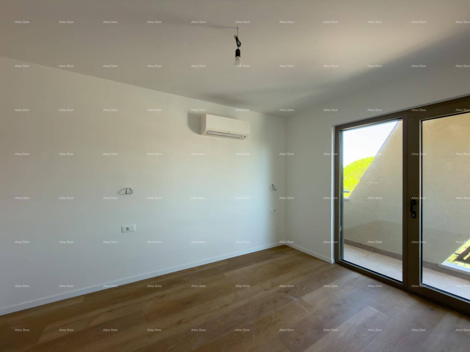 Heller Raum mit Holzboden, Klimaanlage und großem Glaszugang zu einem Balkon.