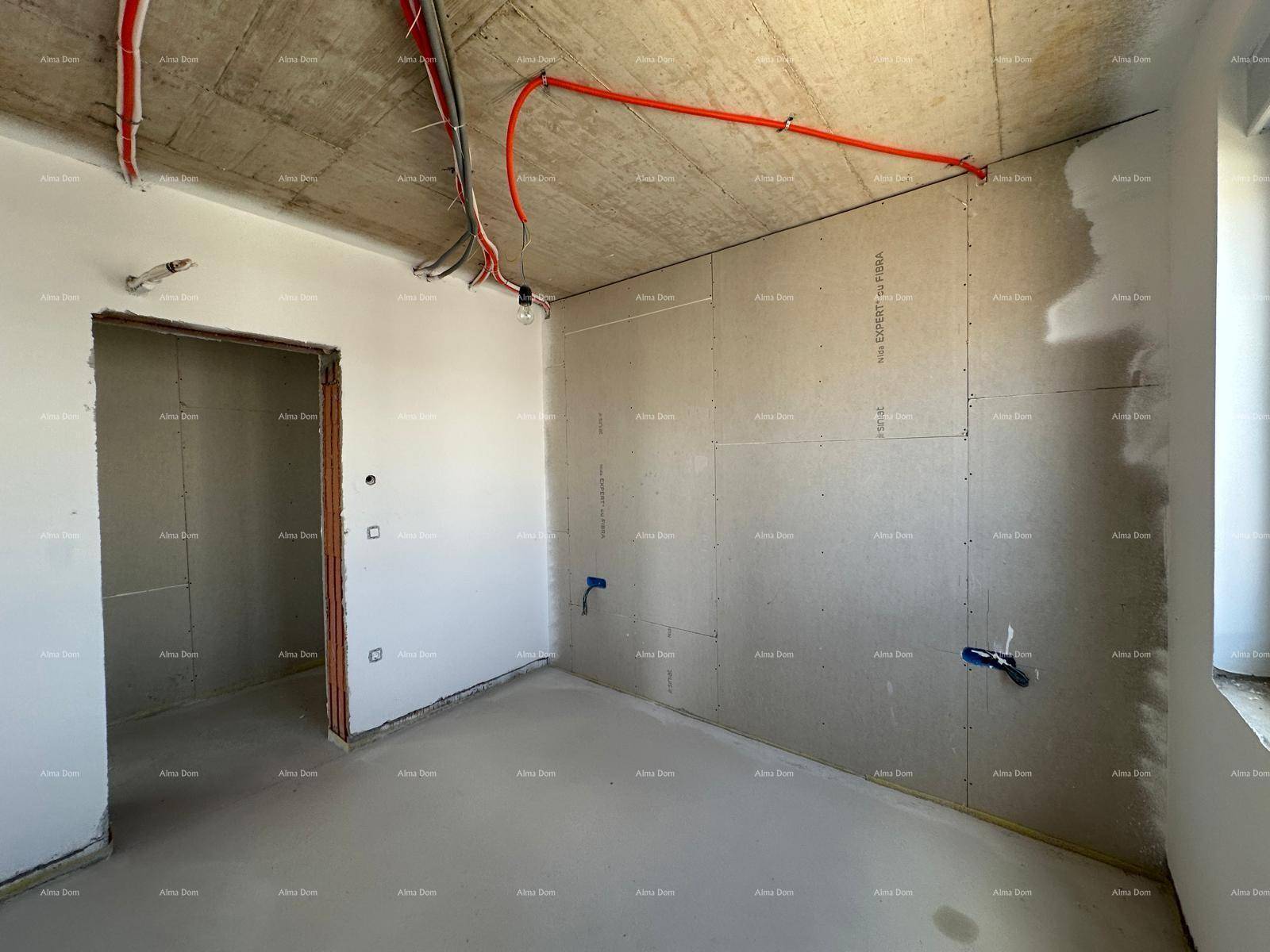 Unfertiger Raum mit Trockenbauwänden und sichtbaren Leitungen an der Betondecke.