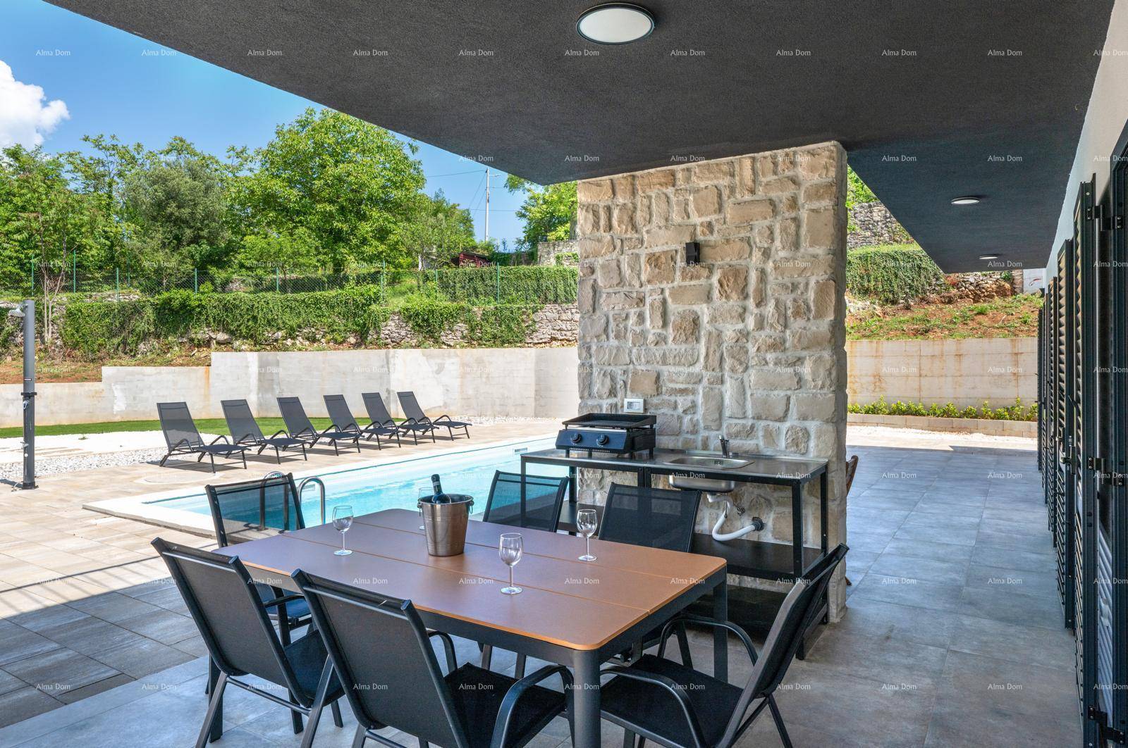 Geräumige überdachte Terrasse mit Esstisch, Außenküche und direktem Zugang zum Poolbereich.