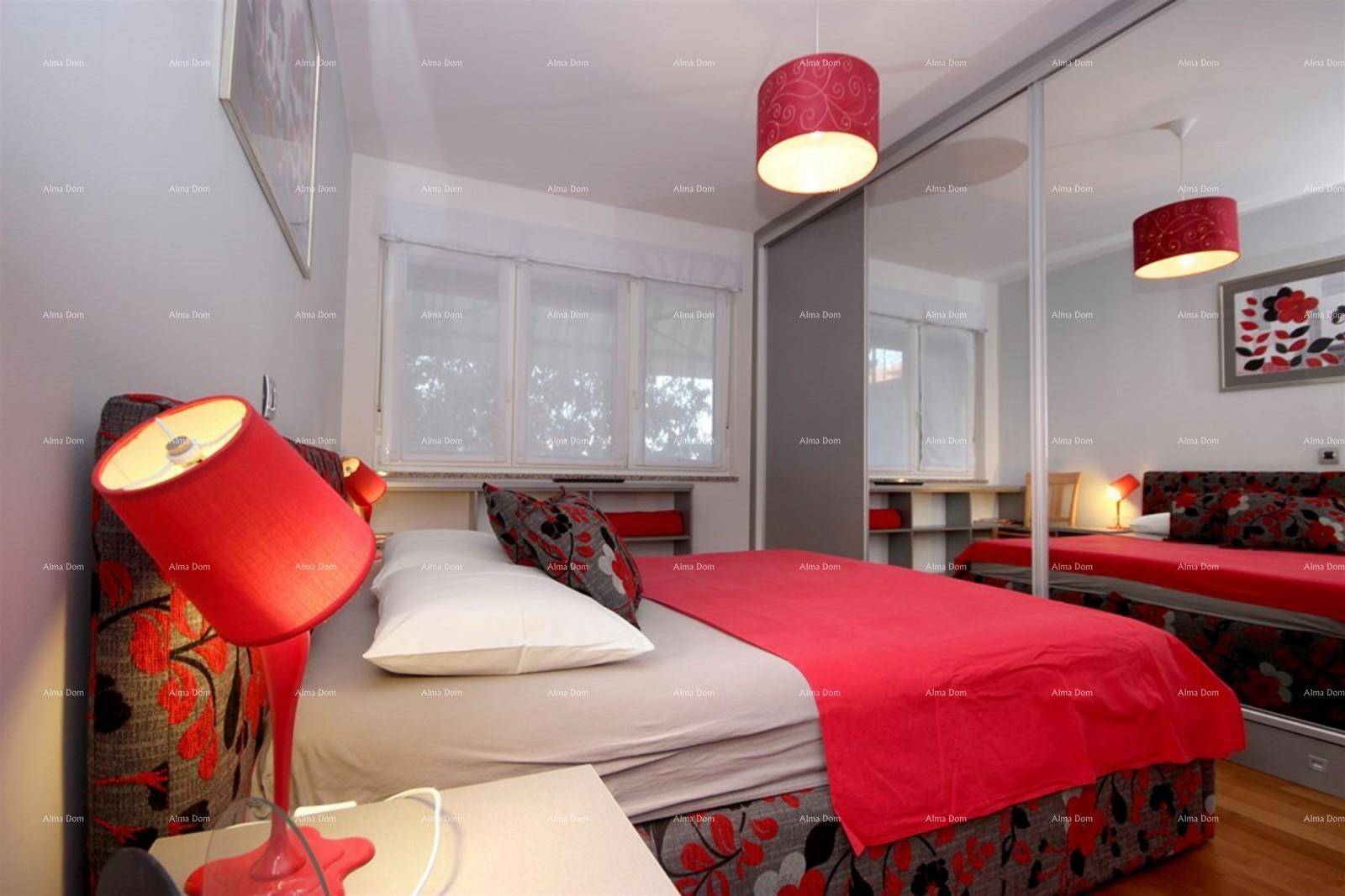 Schlafzimmer mit rotem Bett, Spiegelschrank und Holzboden.