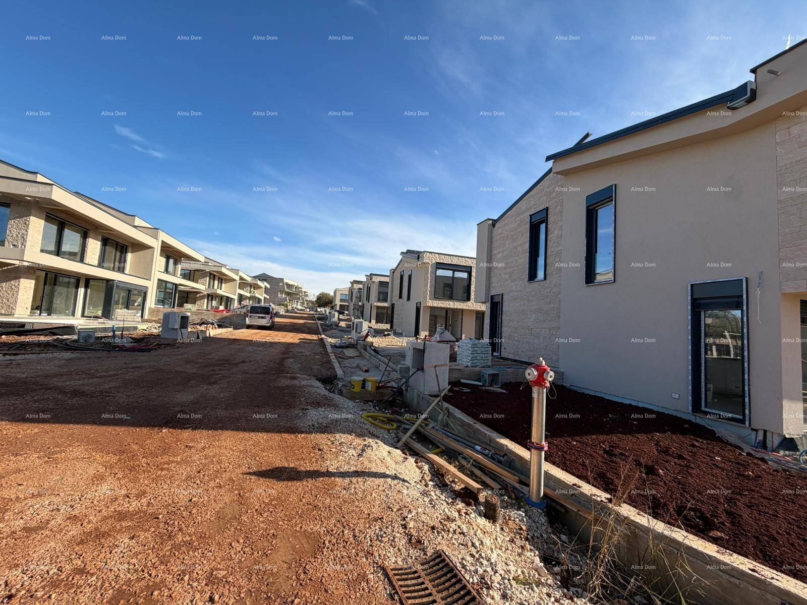 Blick auf die im Bau befindliche Straße und moderne Reihenhäuser in einer neuen Siedlung.