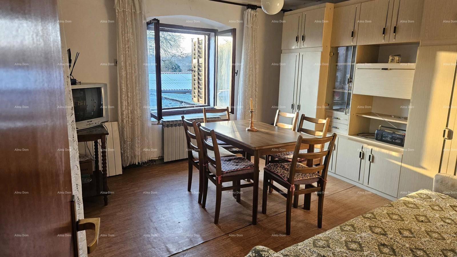 Gemütlicher Essbereich mit Holztisch, Stühlen und einem großen Fenster, das viel Tageslicht hereinlässt.