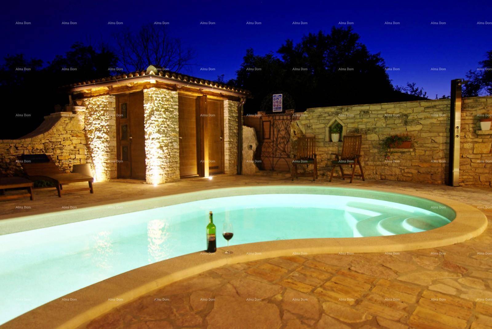 Beleuchteter Poolbereich mit Steinpflaster, einem kleinen Poolhaus und Liegestühlen bei Nacht.