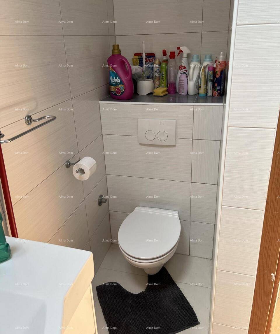 Kleines WC mit wandhängender Toilette und hellen Fliesen, ausgestattet mit Ablagefläche.